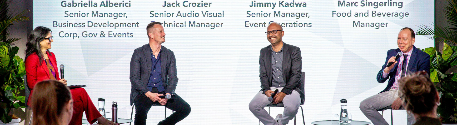 Four panelists from ICC Sydney team speaking in front of projection with their headshot. Projection includes live captioning. Panel is for ICC Sydney's 'Trust in Partnerships: ICC Sydney Operations Update 2024'