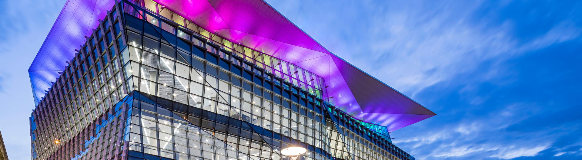 Exterior image of ICC Sydney's Convention Centre lit up in purple and blue.