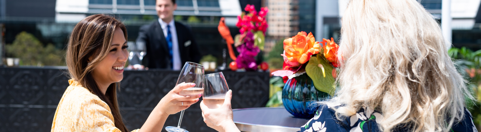 Two women sitting down, enjoying wine on ICC Sydney’s Event Deck.