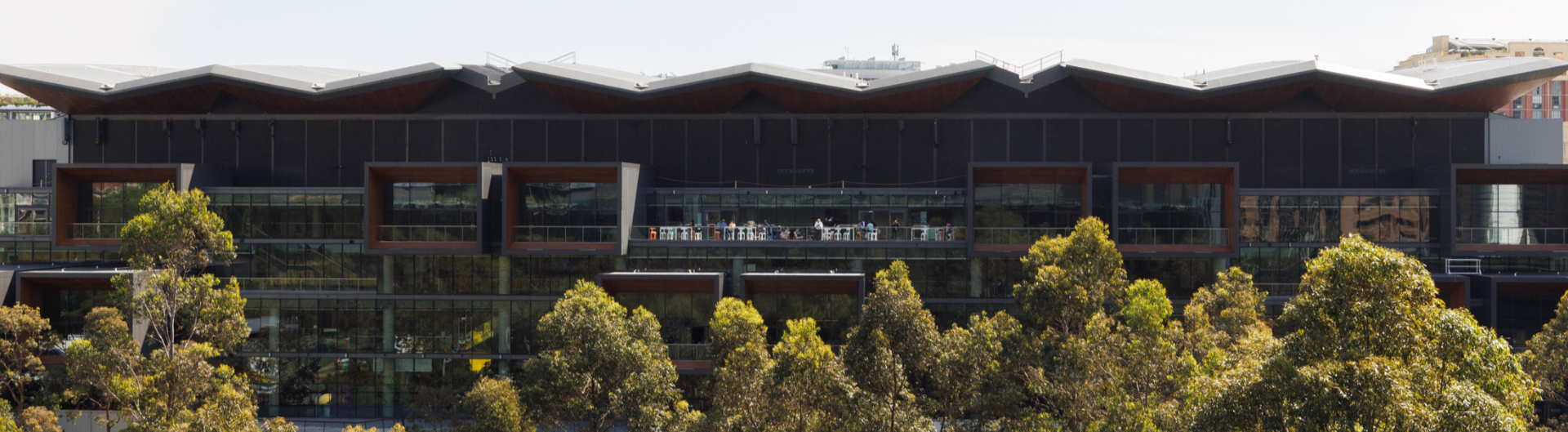 ICC Sydney's exhibition centre surrounded by trees in front of it.