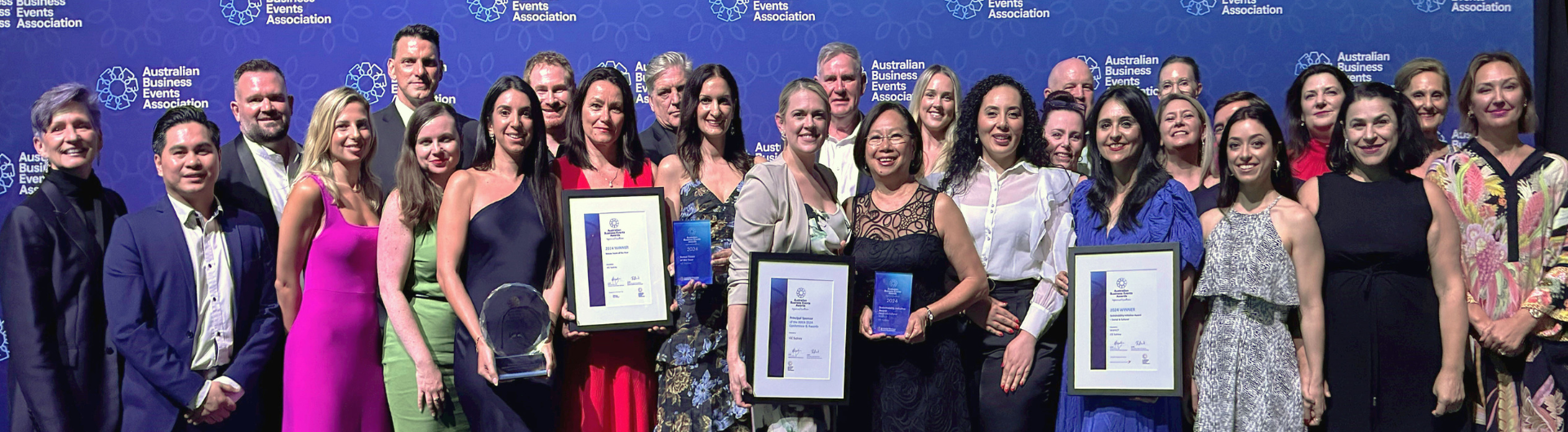 ICC Sydney team poses for camera in front of ABEA media wall, in recognition of winning two accolades at ABEA awards Dinner.