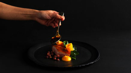 Things to do in Sydney - image of a hand with a spoon touching some food, against a black background.