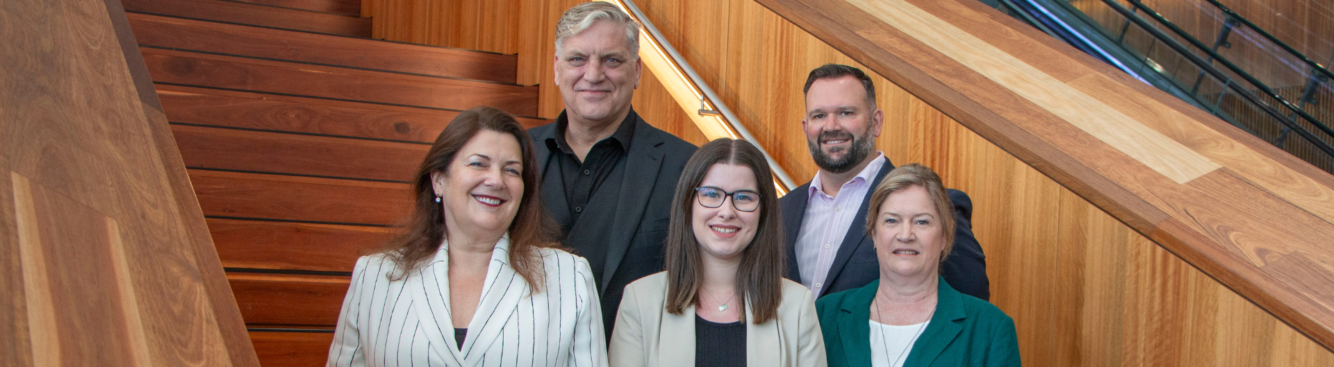 Adam Mather-Brown, Beverley Parker, Luke Fleming, Dr Meg Hibbins, and Emily Howe smile while standing on an ICC Sydney staircase.