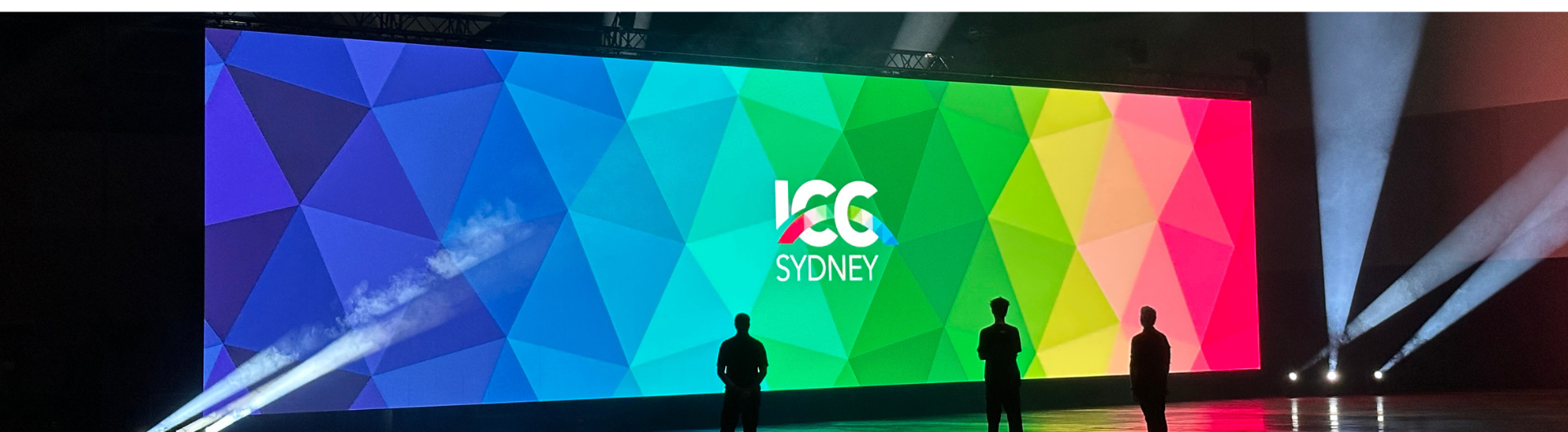 ICC Sydney's LED technology, featuring a screen with the ICC Sydney brand triagulation of rainbow colours, as well as the ICC Sydney logo in the middle. Three silhouettes are shown against the image.