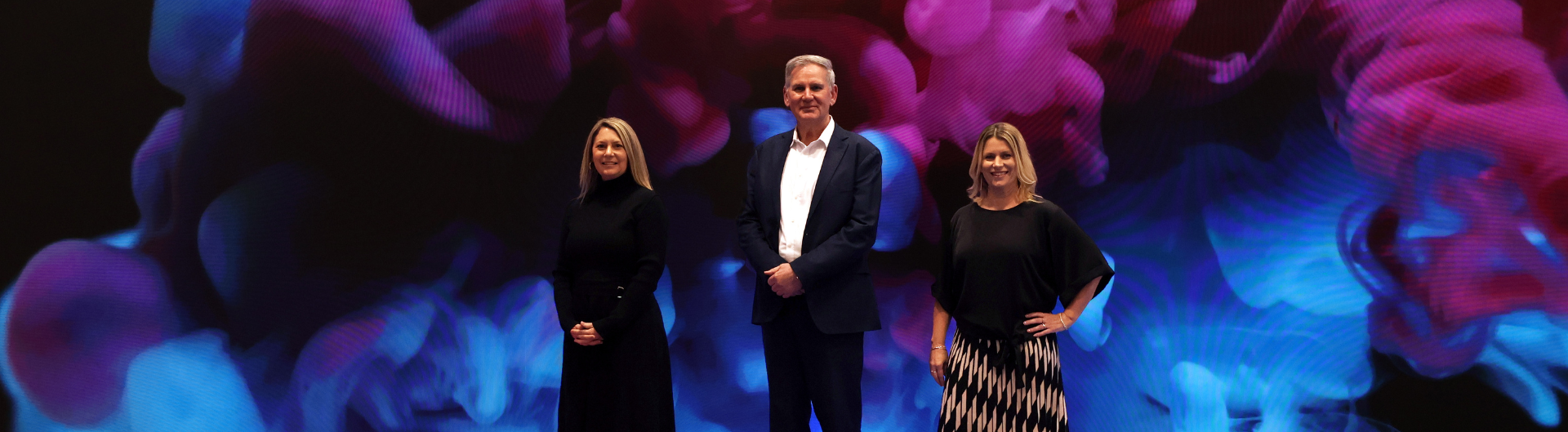 ICC Sydney's LED Activation Zone, featuring a cloud of blue and purple as the image and three presons standing in the middle, smiling at the camera.